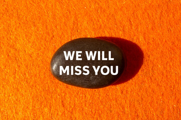 We will miss you message written on black stone on orange background. Conceptual we will miss you symbol. Copy space.