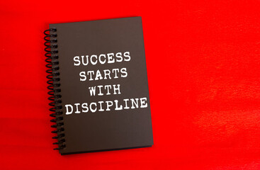 Success starts with discipline message written on black notebook page on red background. Conceptual success starts with discipline symbol. Copy space.