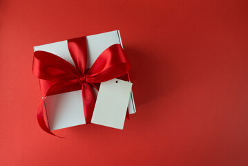 White gift box with red bow on red background