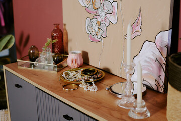High angle shot of wooden dresser with wax candles, accessories and painting on top, copy space