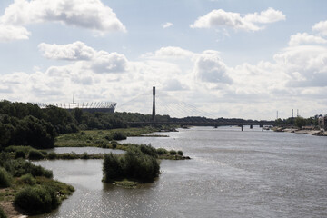Fototapeta premium Calm view of the Vistula River flowing through Warsaw, with nature and city in balance.