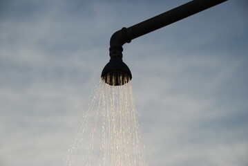 Water Flowing from Showerhead Against Cloudy Sky