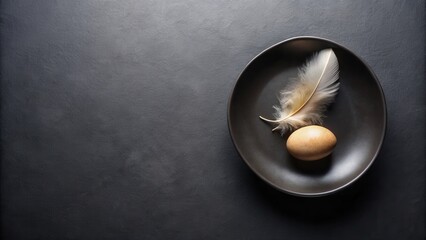 A solitary egg and a delicate feather rest on a dark plate, a minimalist still life composition