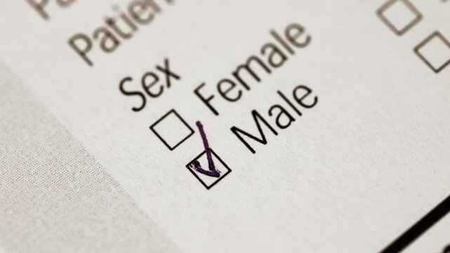 A person fills out a patient information form by selecting the male gender option with a pen, symbolizing healthcare documentation and identity data