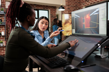 Videogame developing company employees working on alpha build of 3D game project while sitting at desk.