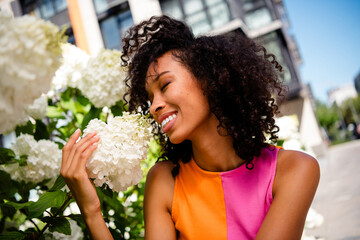 Photo of pretty young woman smell flowers wear colorful clothes walk outside urban recreation city...