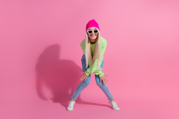 Young fashionable woman posing in bright casual attire against a pink backdrop, showcasing a vibrant and stylish look