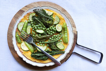  Breakfast. Omelet with zucchini and green peas on white plate. Frittata - Italian omelet.