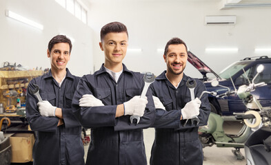 Group of auto mechanic workers in uniforms with tools