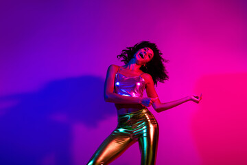 Stylish young woman dancing in a vibrant neon-lit setting, expressing energy and joy in a gradient of purple, pink, and gold hues.