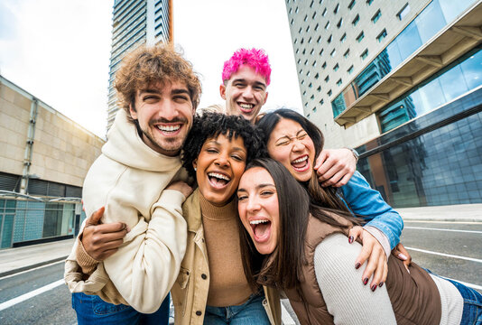 Happy multiracial friends having fun on city street - Group of young people smiling at camera outside - Friendship concept with guys and girls walking in downtown road