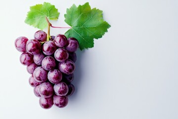 Fototapeta premium A cluster of purple grapes resting on a bright white surface