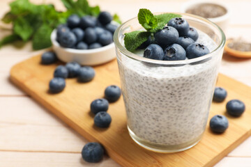 Delicious chia pudding with blueberries and mint in glass on wooden table, closeup