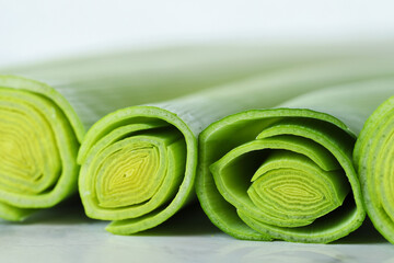 Whole fresh leeks on white marble table, closeup