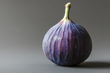 Fototapeta premium A single ripe fig fruit displayed against a neutral grey background