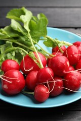 Many fresh radishes on black wooden table, closeup