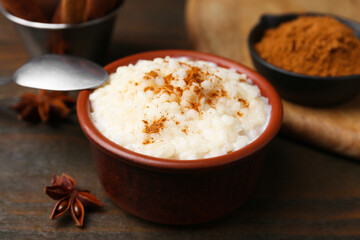 Tasty rice pudding with cinnamon served on wooden table, closeup