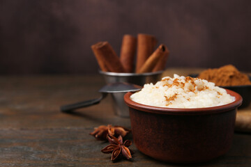 Tasty rice pudding with cinnamon served on wooden table, closeup. Space for text