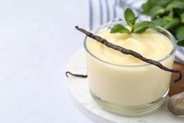 Tasty vanilla pudding, mint and pods on white table, closeup. Space for text