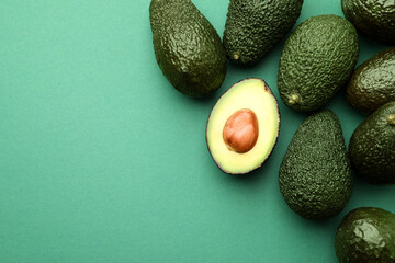 Fresh ripe avocados on teal background, flat lay. Space for text