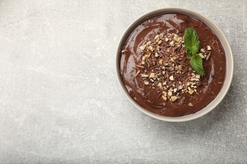Delicious chocolate mousse in bowl on grey table, top view. Space for text