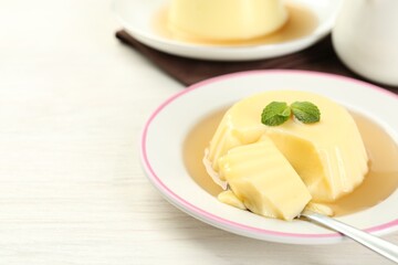 Delicious pudding with caramel sauce and mint served on white table. Space for text