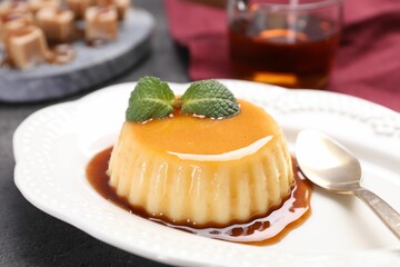 Delicious pudding with caramel sauce and mint served on table, closeup