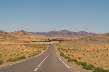 long road in the desert with mountains and blue sky 