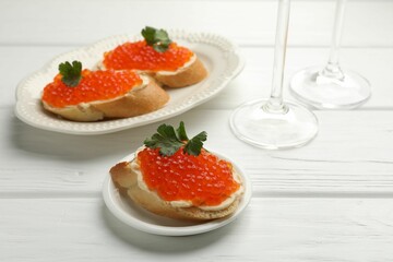 Tasty sandwiches with red caviar on white wooden table, closeup