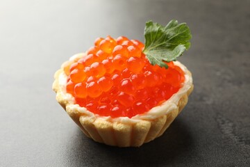 Tasty canape with red caviar on grey table, closeup