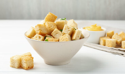 Delicious crispy croutons with parsley and sauce on white wooden table, closeup