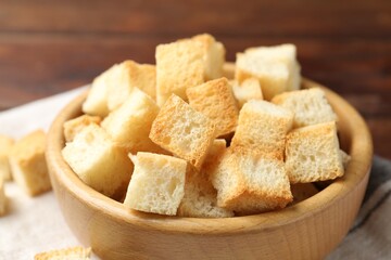 Delicious crispy croutons in bowl on table, closeup