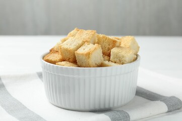 Delicious crispy croutons on white table, closeup