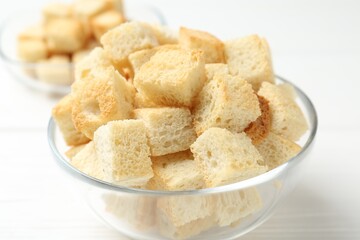 Delicious crispy croutons on white wooden table, closeup