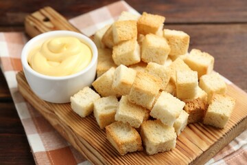 Delicious crispy croutons with sauce on wooden table, closeup