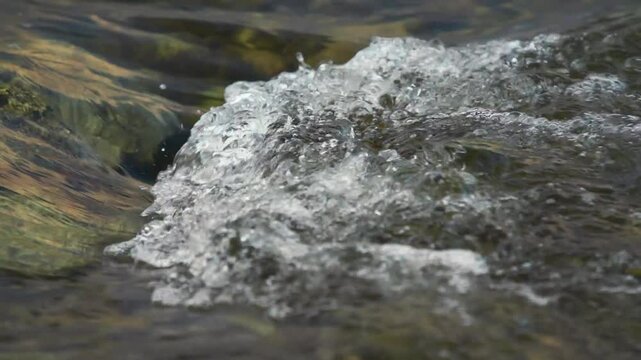 Clear water flowing over rock in a river, closeup detail, 2x Slow motion video