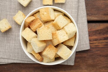 Delicious crispy croutons on wooden table, flat lay