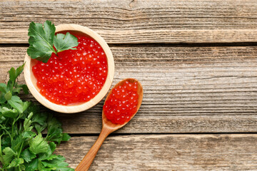 Red caviar and parsley on wooden table, flat lay. Space for text
