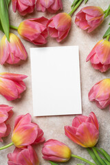 Blank invitation or greeting card mockup with fresh tulips flowers composition, top view with copy space