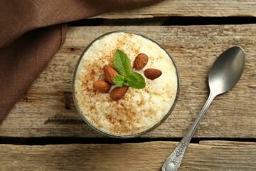 Delicious rice pudding with cinnamon, almonds and mint served on wooden table, top view