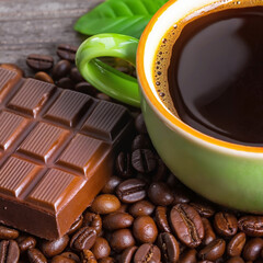 green cups of coffee with roasted coffee beans and a chocolate bar.