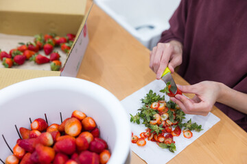 Person trimming fresh strawberries on a table