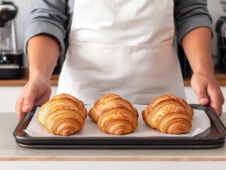 coffee and bakery concept. Cappuccino recipe card next to a baking sheet of croissants, with a kitchen counter full of baking tools and coffee-making equipment