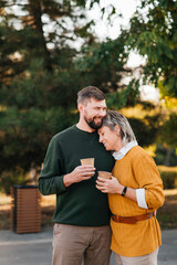 Happy couple walking with glasses of hot drink