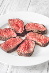 Perfectly sliced medium-rare fillet mignon steak served on a white plate