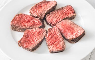 Perfectly sliced medium-rare fillet mignon steak served on a white plate