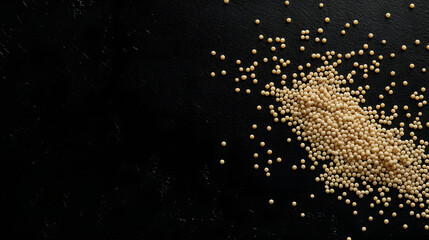 Obraz premium Amaranth grains arranged in a subtle, scattered pattern on a dark, smooth surface.