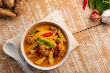 Thai red curry soup with pork and yam(Dioscorea esculenta yam),boiled sliced pork with red curry paste and coconut milk in white bowl.Top view.