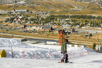 The top of the ski hill with a snowboarder riding downhill