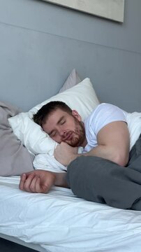 Young man is sleeping well in bed in bedroom in the morning